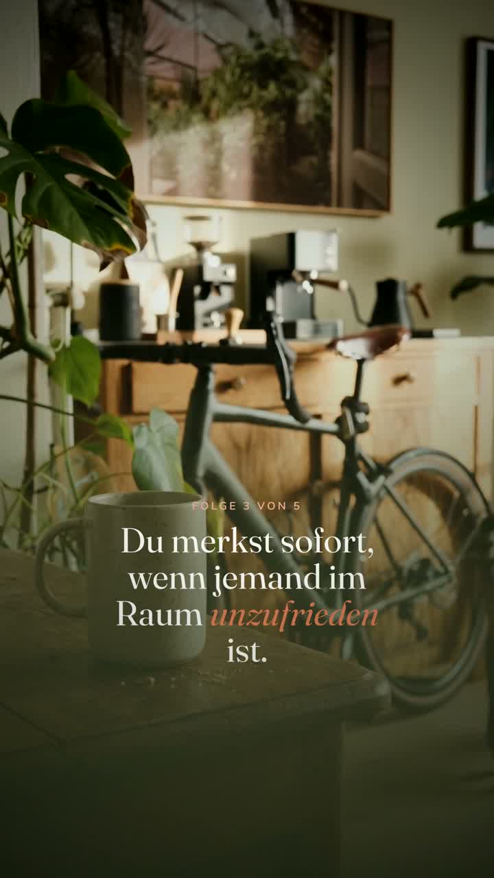 Ein cognacfarbener Ledersessel, daneben eine große Pflanze am Fenster.