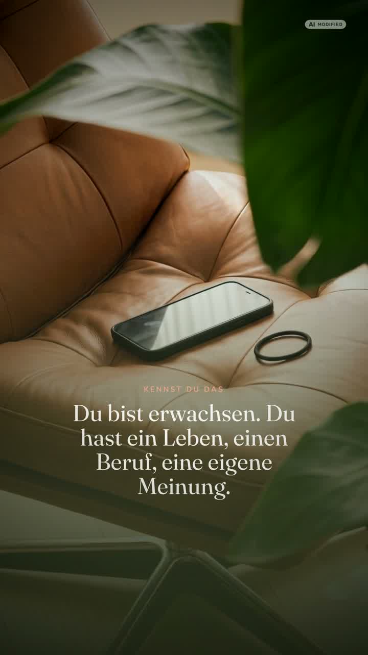 Ein Telefon liegt auf einem Ledersessel, davor eine Pflanze und eine Katze.